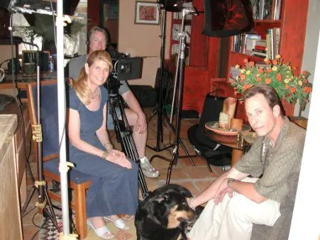 Film crew with actors and dog on set.