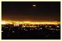 Here's a short alt tag for the image: `Night lights over city with UFO`