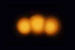 Here's a short alt tag for the image: Three blurry orange lights in darkness.