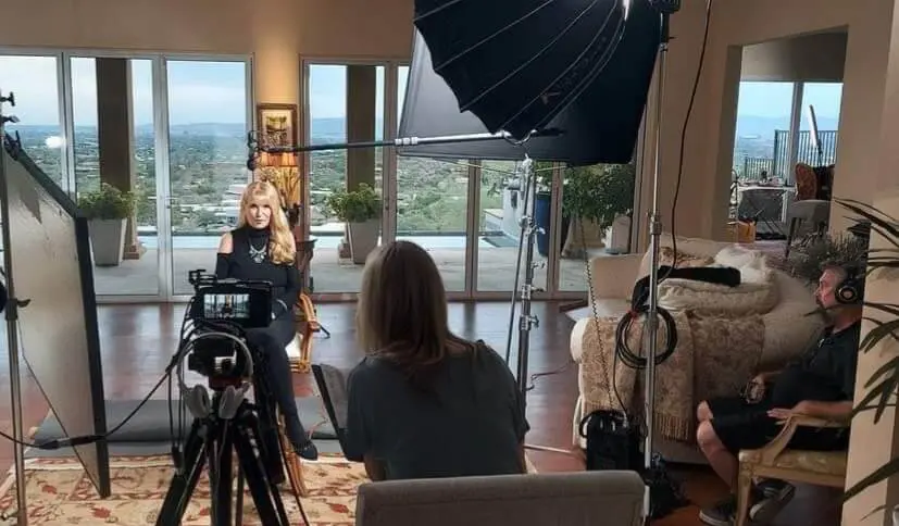 Film crew interviewing woman in luxury home.